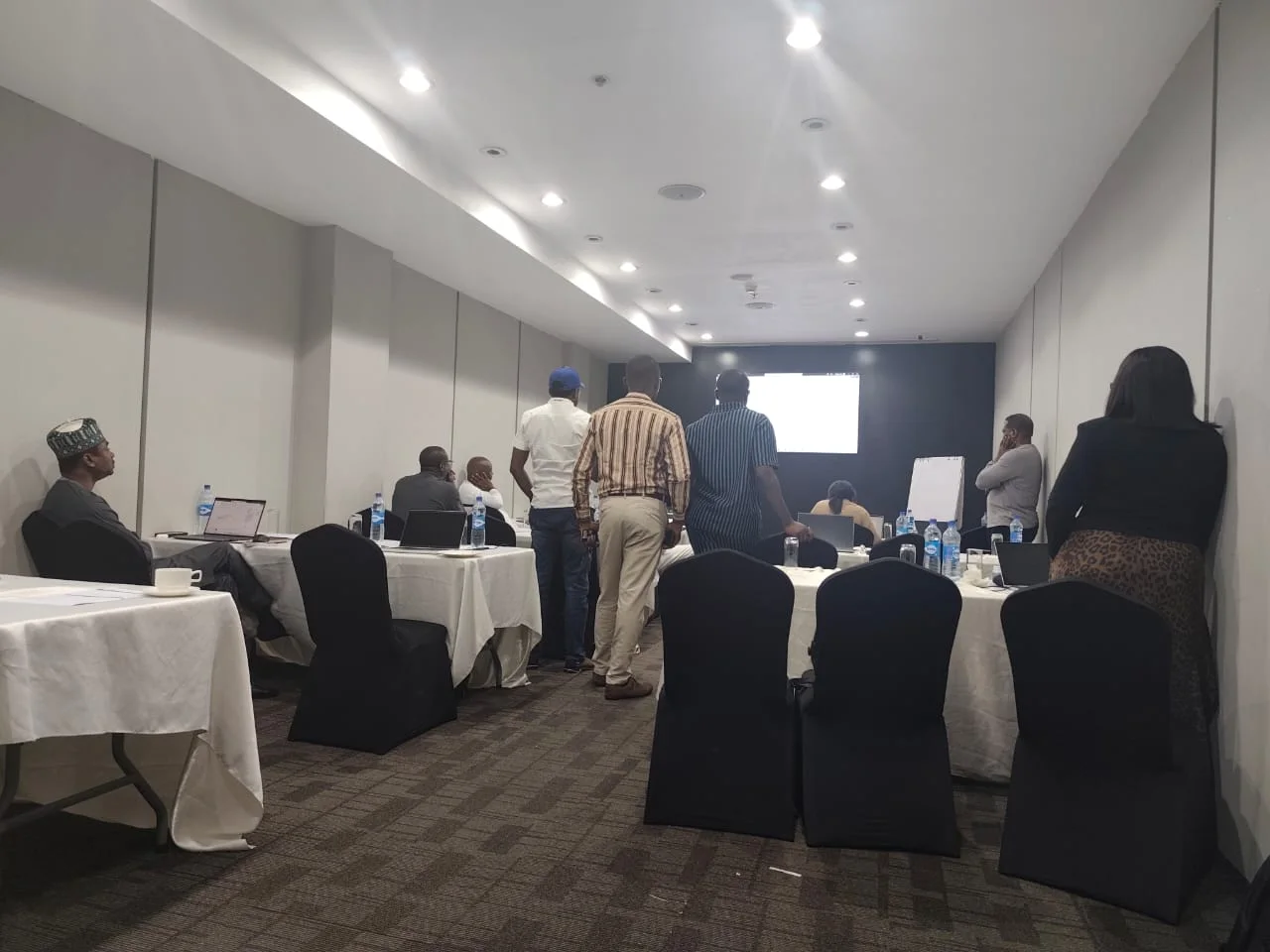 Participants stand and discuss an activity at the front of the room.