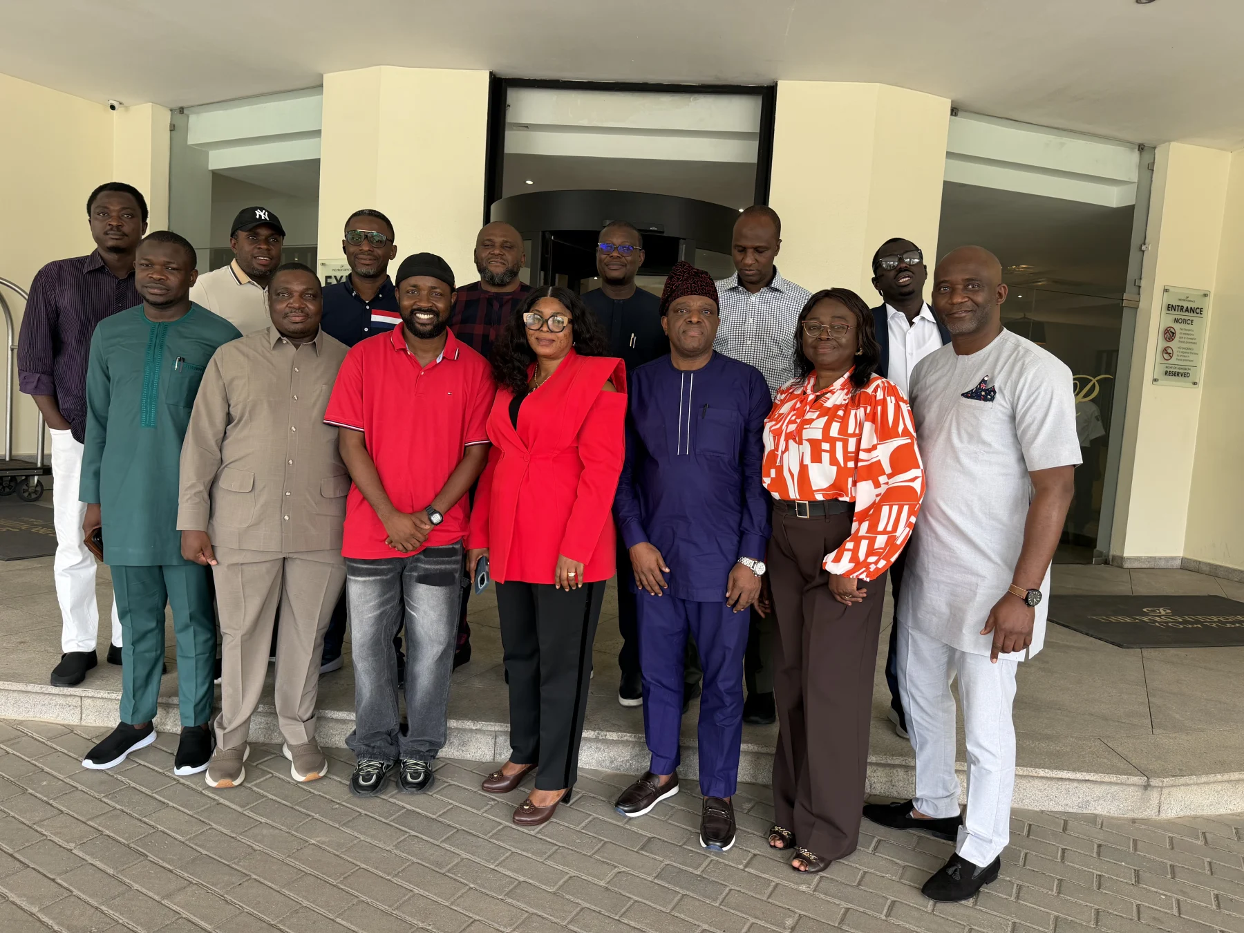 A wider view of the group posing outside a building.